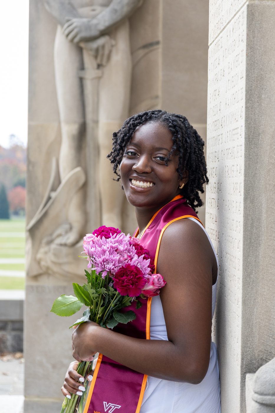 Graduate holding pink flowers