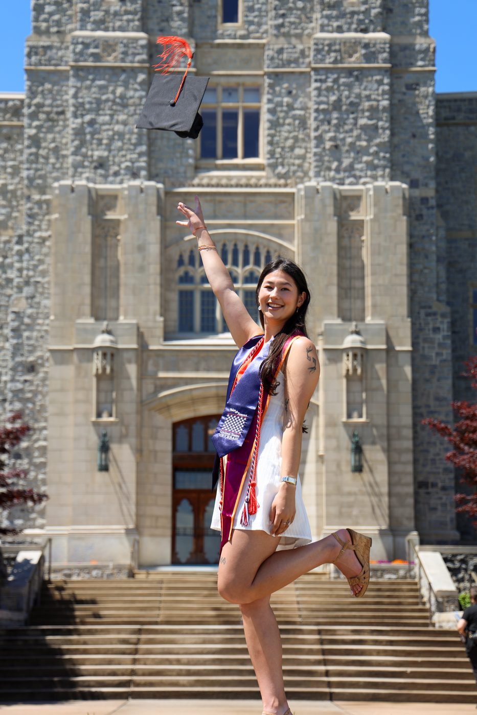 Graduate throwing cap in front of Burruss Hall
