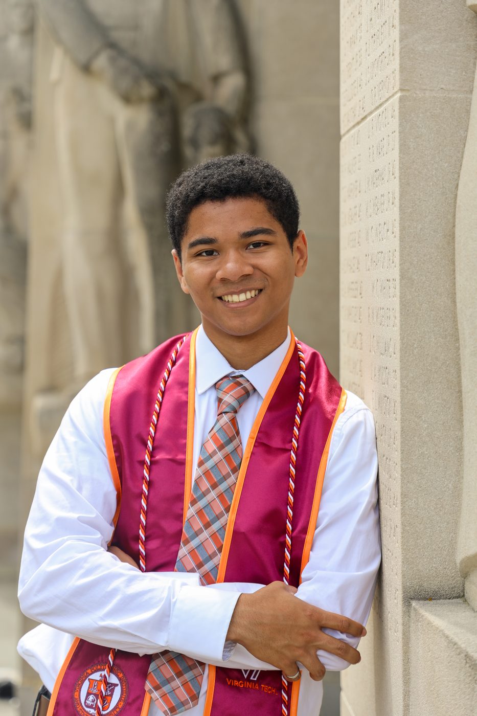 Graduate leaning on engraved wall