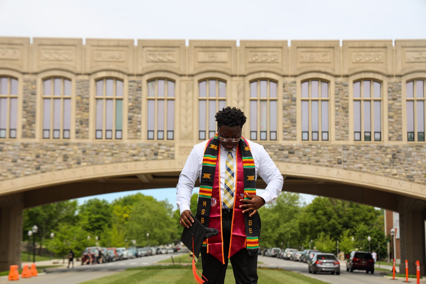 Graduate in kente stole in front of Torgersen Bridge