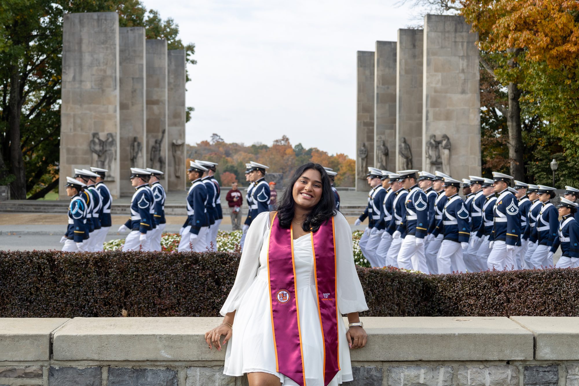 Graduate smiling at the war memorial as cadets march past